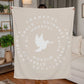 Fleece blanket with a dove at the center, surrounded by circles of words like 'Thankful,' 'Peace,' 'Joy,' and 'Faith,' on a warm background.
