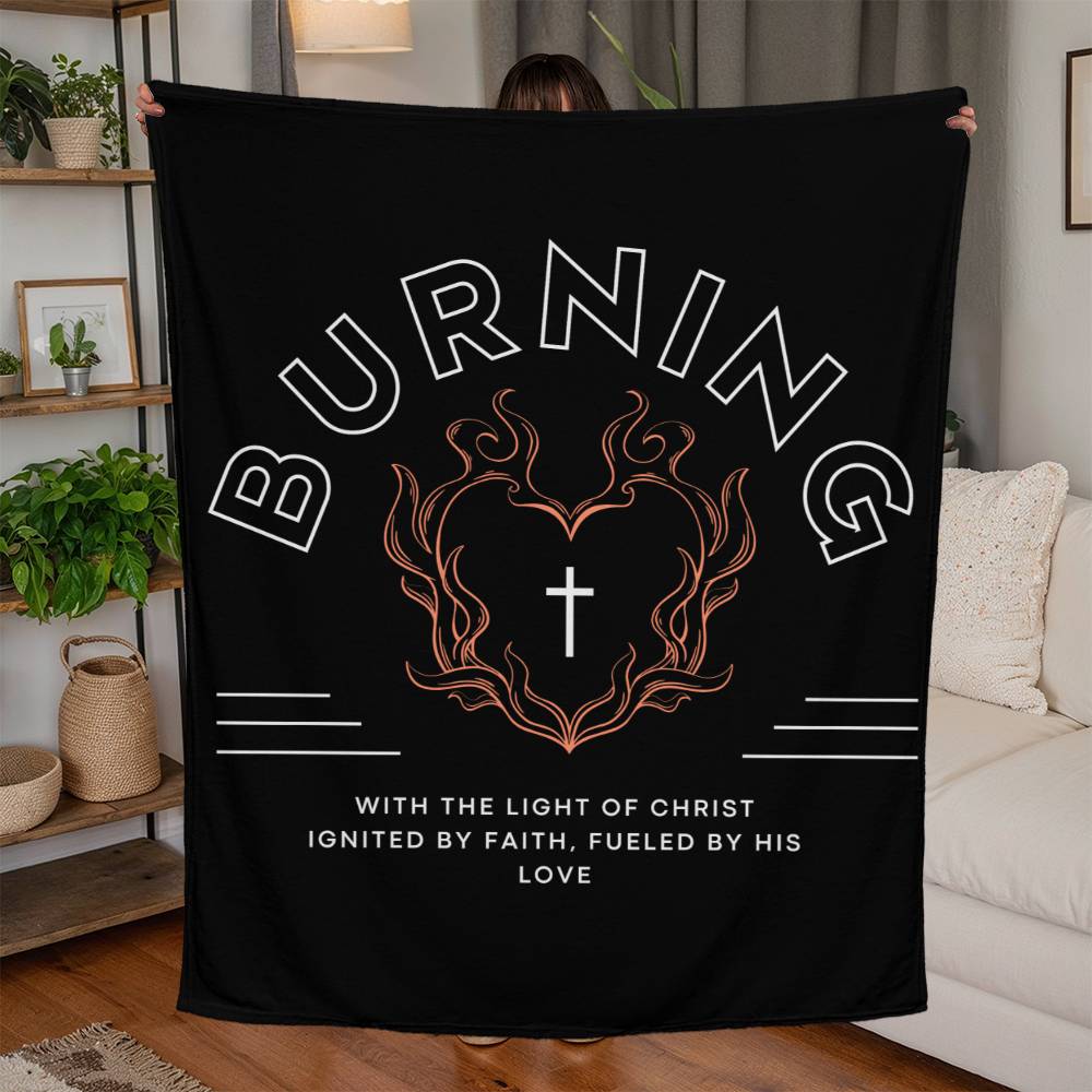 Black fleece blanket with white text, featuring 'Burning with the Light of Christ' message, heart-shaped flame, and cross biker-style design.
